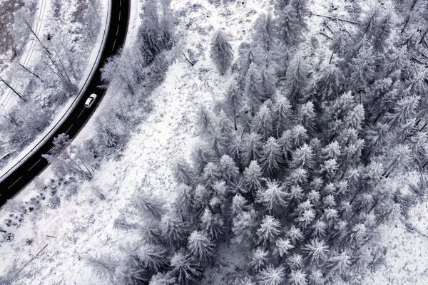 Вид сверху на автодорогу вдоль заснеженных лесов в горах Гарц близ Вернигероде в Германии. - Sputnik Казахстан