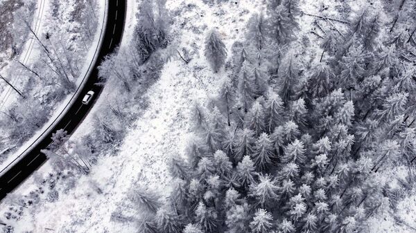 Автомобиль проезжает по заснеженному ландшафту в горах Гарц недалеко от Ширке, Германия - Sputnik Қазақстан