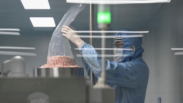Человек в защитном костюме работает на производственной линии фармацевтической фабрики - Sputnik Казахстан