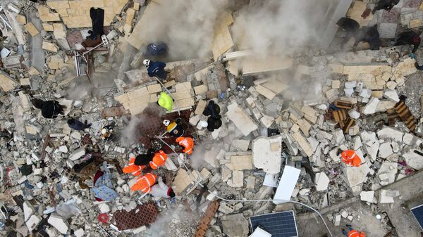 Поиски жертв и выживших под обломками рухнувших зданий после землетрясения в городе Сармада в сирийской провинции Идлиб  - Sputnik Казахстан