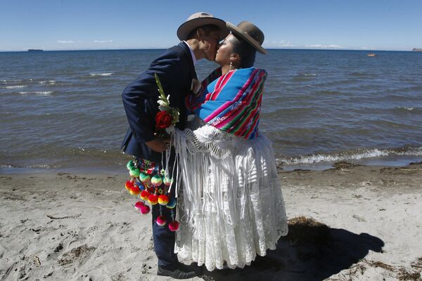 Пара молодоженов  дарят друг другу поцелуи во время свадебной церемонии на берегу озера Титикака в Перу. - Sputnik Казахстан