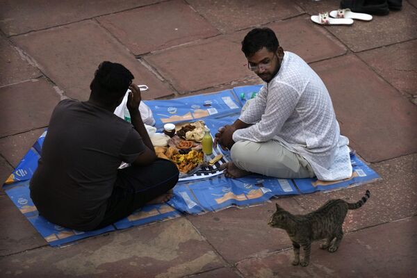 На Рамадан верующие воздерживаются от приема пищи и питья в светлое время суток. На фото: мужчины принимают пищу в первый день священного месяца Рамадан в Джама Масджид в Нью-Дели, Индия. - Sputnik Казахстан