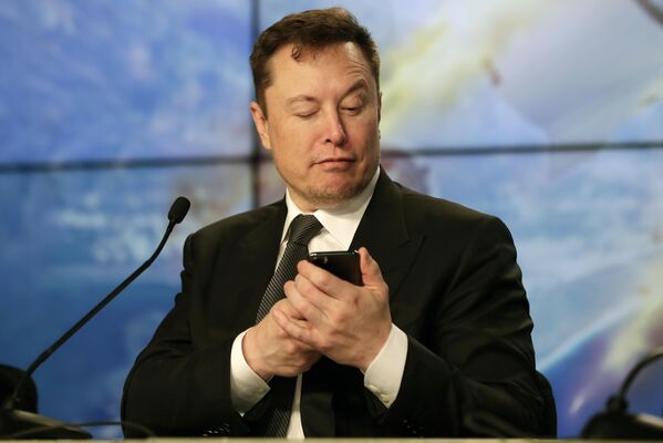 На этом фото основатель SpaceX Илон Маск веселит журналистов, делая вид, что ищет ответ на вопрос по мобильному телефону во время пресс-конференции после испытательного полета ракеты Falcon 9 SpaceX. - Sputnik Казахстан