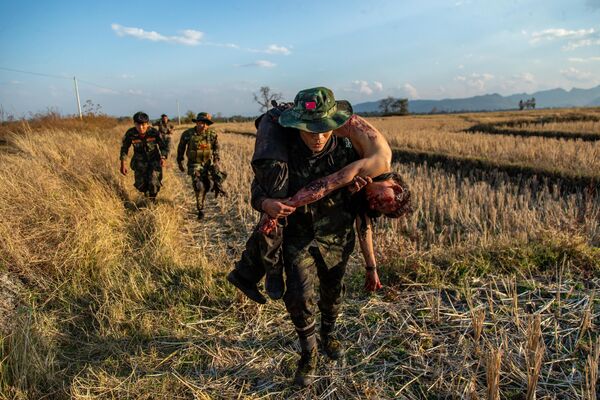 На снимке бойцы сопротивления из Народных сил обороны отступают, неся на плечах тело своего погибшего товарища после столкновения с военными Мьянмы.  - Sputnik Казахстан