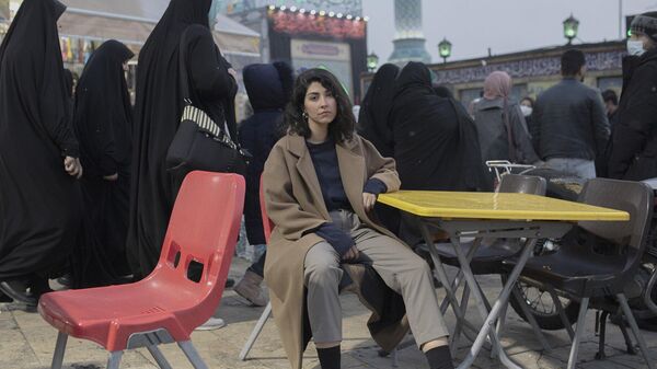 Иранская женщина на стуле на площади в Тегеране без обязательного для ношения хиджаба.  - Sputnik Казахстан