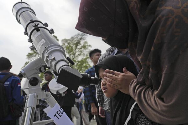 Первое затмение 2023 года называют гибридным (кольцеобразно-полным) солнечным. На фото: люди наблюдают за солнечным затмением 2023 года в Индонезии. - Sputnik Казахстан