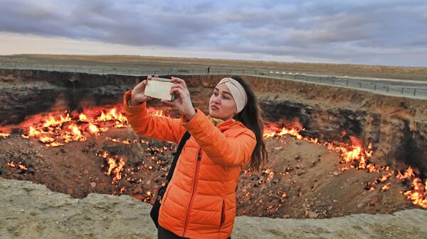 Девушка делает селфи на фоне горящего кратера Врата ада, пустыня Каракумы, Туркменистан - Sputnik Қазақстан