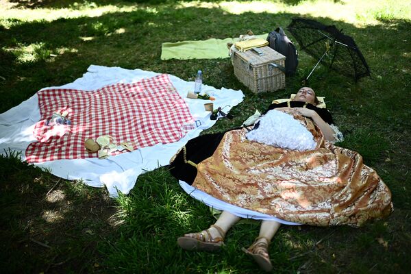 Женщина, одетая в костюм XVII века, отдыхает в тени дерева, принимая участие в &quot;Большом путешествии костюмеров&quot;, историческом мероприятии, собирающем сотни людей в замке Во-ле-Виконт в Майнс, Франция. - Sputnik Казахстан