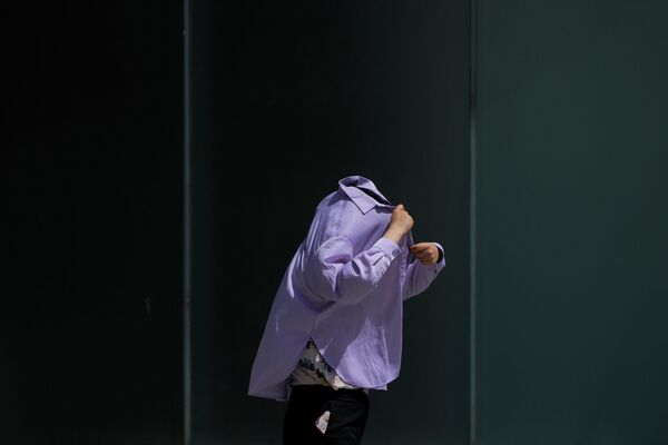 Женщина использует рубашку с длинным рукавом, чтобы защититься от палящего солнца в Пекине, Китай.  - Sputnik Казахстан