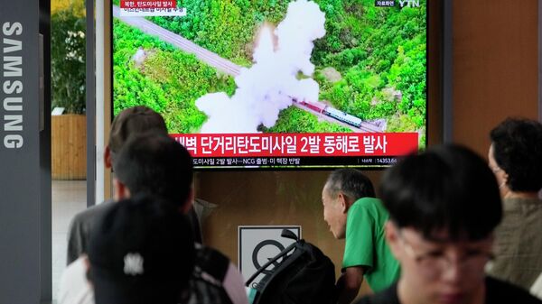 Люди на станции в Сеуле наблюдают за запуском ракеты в Северной Корее  - Sputnik Казахстан