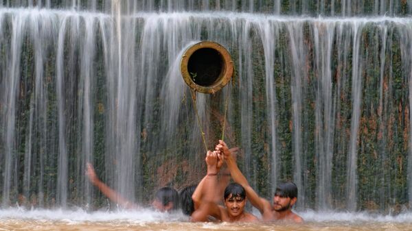 Молодые люди освежаются в водопаде, когда температура достигла 36 градусов по Цельсию в Исламабаде, Пакистан - Sputnik Казахстан