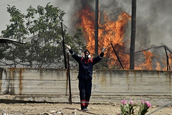 Пожарный на фоне лесного пожара в поселении Панорама близ Агиои Теодори, примерно в 70 км к западу от Афин. - Sputnik Казахстан