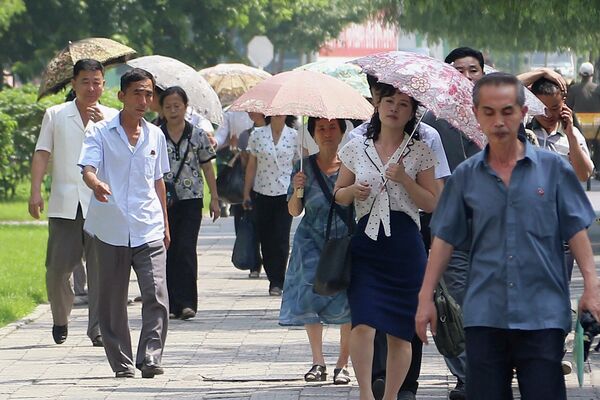 Прохожие прячутся под зонтами от жаркого солнца в Пхеньяне, Северная Корея. - Sputnik Казахстан