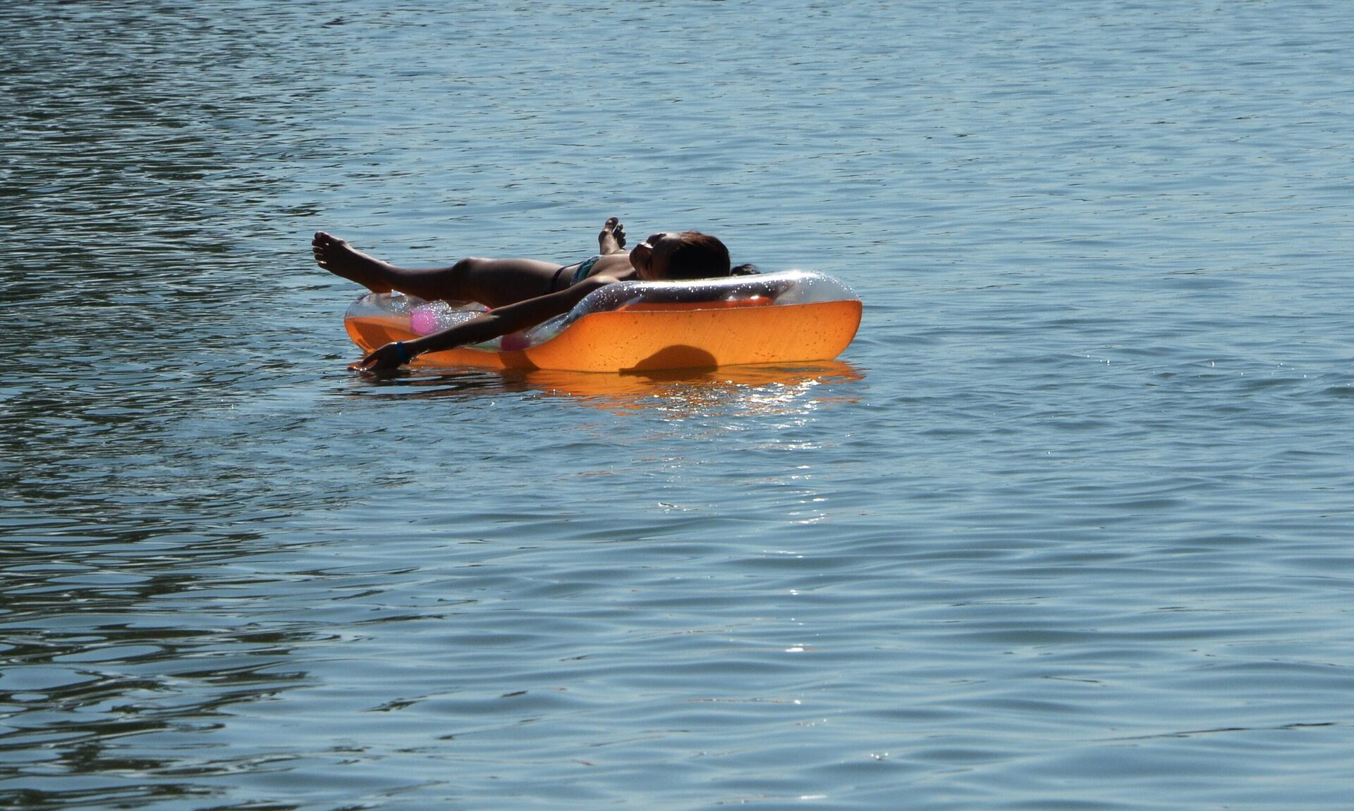 Девушка загорает на надувном матрасе. - Sputnik Казахстан, 1920, 19.08.2025