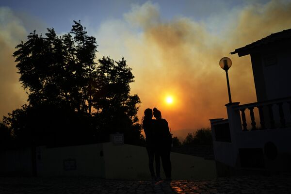 Женщины наблюдают за лесным пожаром возле домов в Алькабидече, недалеко от Лиссабона, Португалия.  - Sputnik Казахстан