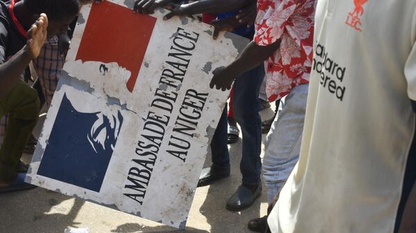 Участник митинга в Нигере держит табличку посольства Франции - Sputnik Казахстан