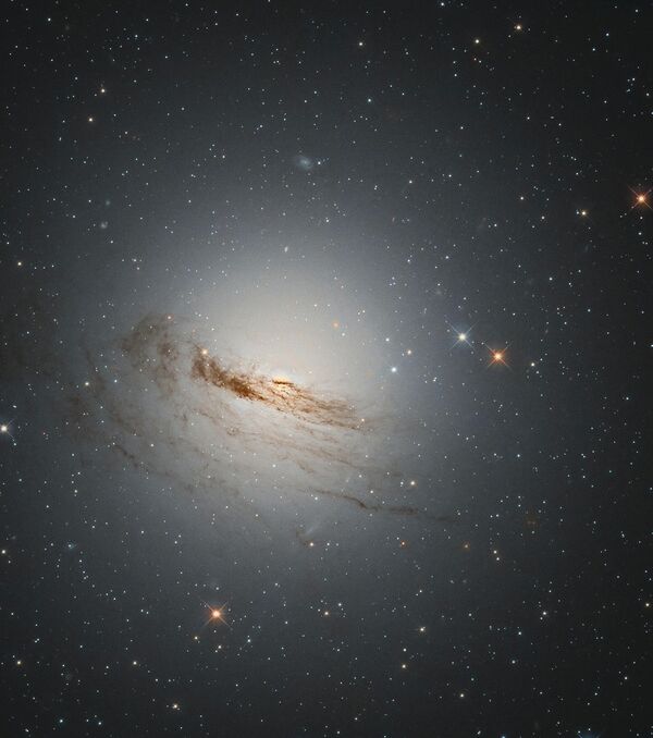 Внешняя оболочка звезды будет остывать и рассеиваться, образуя множество тонких облаков, расширяющихся пузырей или туманностей. На фото: необычная линзовидная галактика, известная как NGC 1947, расположена на расстоянии около 40 млн световых лет от Земли. На снимке видны слабые остатки спиральных рукавов галактики. Без большей части звездообразующего материала маловероятно, что в NGC 1947 родится много новых звезд, в результате чего эта галактика будет продолжать угасать со временем. - Sputnik Казахстан