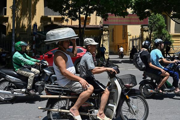 Мужчина, едущий на мотоцикле, использует алюминиевый тазик вместо шляпы от солнца. Во Вьетнаме, как и во многих других странах мира, тоже выдалось жаркое лето.  - Sputnik Казахстан