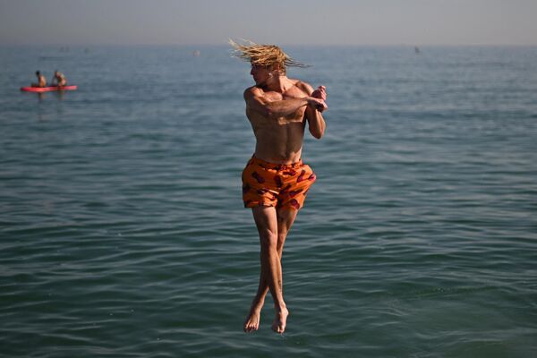 &quot;Танец маленьких лебедей. Современная версия&quot;. На фото: мужчина прыгает в море с пляжа в Брайтоне, Великобритания. - Sputnik Казахстан