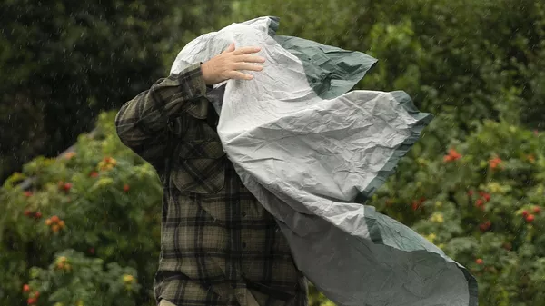 Турист борется со своим дождевым пончо во время сильного ветра, США - Sputnik Казахстан