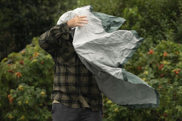 Турист борется со своим дождевым плащом во время сильного ветра в Бар-Харборе, штат Мэн. На ряд здешних регионов на этой неделе обрушился мощный ураган Ли.  - Sputnik Казахстан