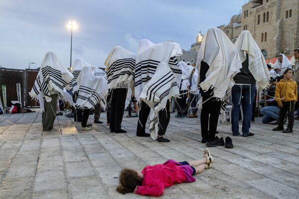 Ребенок отдыхает, пока взрослые мужчины совершают обряд во время недельного религиозного праздника Суккот, Израиль. - Sputnik Казахстан
