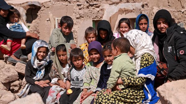 Афганские дети сидят возле своих поврежденных домов после землетрясения в деревне Вардакха - Sputnik Қазақстан