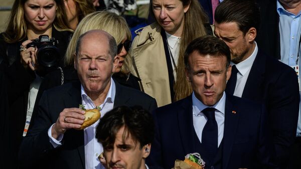 Канцлер Германии Олаф Шольц (слева) и президент Франции Эммануэль Макрон едят бутерброд с рыбой на пирсе в Гамбурге, Германия - Sputnik Казахстан