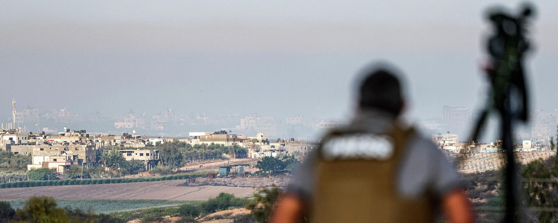Журналист сидит с камерой и наблюдает с позиции в южно-израильском городе Сдерот за горизонтом северной части сектора Газа во время израильской бомбардировки - Sputnik Қазақстан, 1920, 10.11.2023