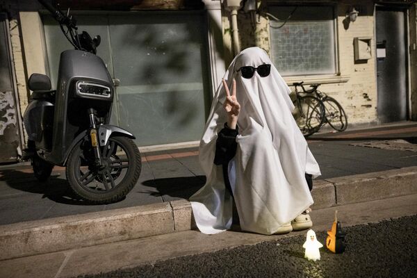 Человек в костюме приведения сидит на тротуаре накануне Хэллоуина в Шанхае. - Sputnik Казахстан