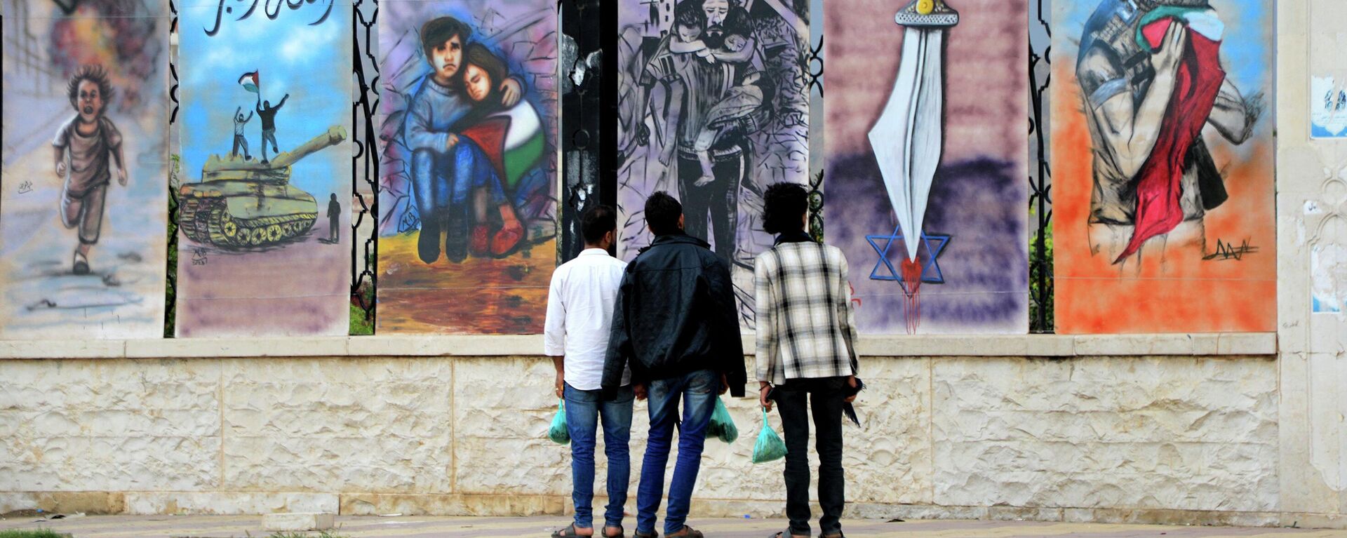 Мужчины смотрят на граффити в знак солидарности с палестинцами сектора Газа и Западного берега, нарисованное на стене мечети на площади Сабин в Сане - Sputnik Казахстан, 1920, 30.03.2024