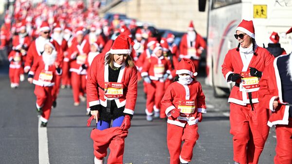 Участница поправляет штаны Санта-Клауса в традиционном рождественском забеге Санта-Клауса в Будапеште, Венгрия - Sputnik Казахстан