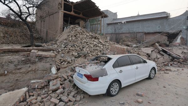 Обрушенные здания и поврежденный автомобиль после землетрясения в Дахэцзя, уезд Цзишишань, провинция Ганьсу на северо-западе Китая - Sputnik Казахстан
