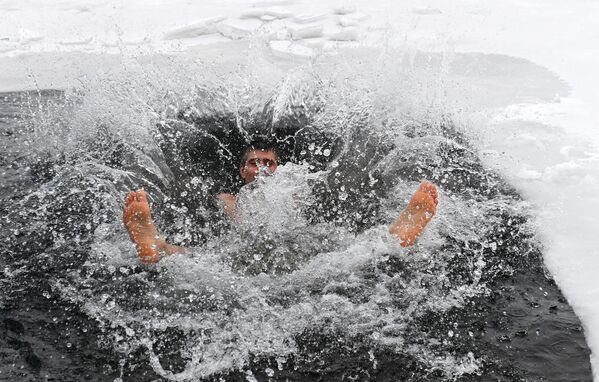 Член спортивно-оздоровительного клуба по плаванию в холодной воде купается в ледяной полынье на реке Енисей во время предновогоднего празднования с одноклубниками в Красноярске. - Sputnik Казахстан