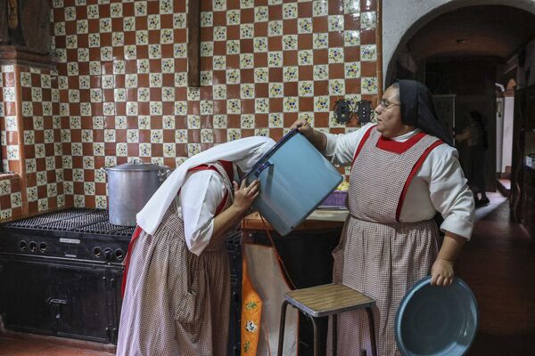 Монахиня Мария де Хесус Фрейл опускает голову в кастрюлю, чтобы понюхать еду в Мехико, Мексика. - Sputnik Казахстан