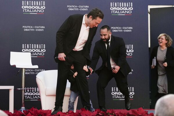 Охранник помогает за кулисами сыну генерального директора Tesla и SpaceX Илону Маску, обнимающему ногу своего отца в Риме, Италия. - Sputnik Казахстан