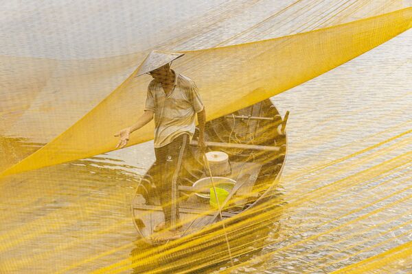 &quot;Вьетнам. Ранним утром на реке Ту Бон недалеко от Хойана в летние месяцы вы можете увидеть рыбаков, поднимающих сети, чтобы посмотреть на свой улов. Сфотографировав рыбака несколькими месяцами ранее, я спросил владельца лодки, который взял меня с собой, как близко мы могли бы подойти к сети. К ее чести, она смогла подвести лодку вплотную к сети, а я смог снимать сквозь сетку, чтобы создать более отчетливое изображение&quot;, - рассказал британский фотограф Julian Elliott. - Sputnik Казахстан
