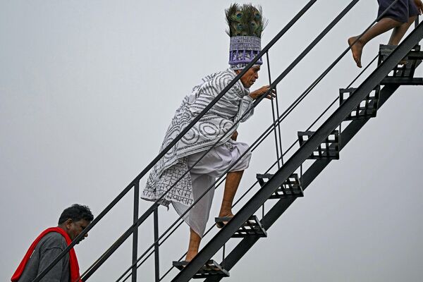 Член религиозного движения Рамнами поднимается по лестнице во время индуистского фестиваля Рамнами Самадж, Индия. - Sputnik Казахстан