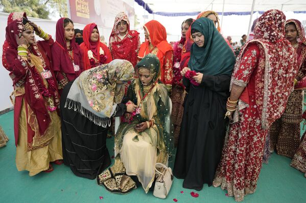 Выйти замуж в Индии — дорогое удовольствие. Поэтому такие мероприятия часто проходят в рамках акции помощи молодым людям в сезон свадеб в стране, у которых нет собственных средств на пышное торжество. На фото: волонтеры помогают невесте во время массовой свадьбы в Ахмадабаде. - Sputnik Казахстан