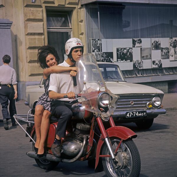 Счастливая влюбленная девушка с парнем на мотоцикле едут по одной из улиц Москвы. - Sputnik Казахстан
