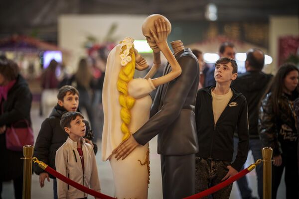 А если променяешь меня на другую, угадай, что с тобой будет? На фото: люди смотрят на инсталляцию целующейся пары скелетов в Бухаресте, Румыния. - Sputnik Казахстан