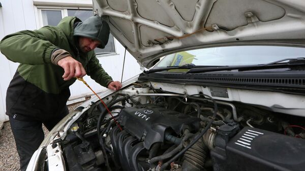 Мужчина проверяет уровень масла в двигателе - Sputnik Казахстан