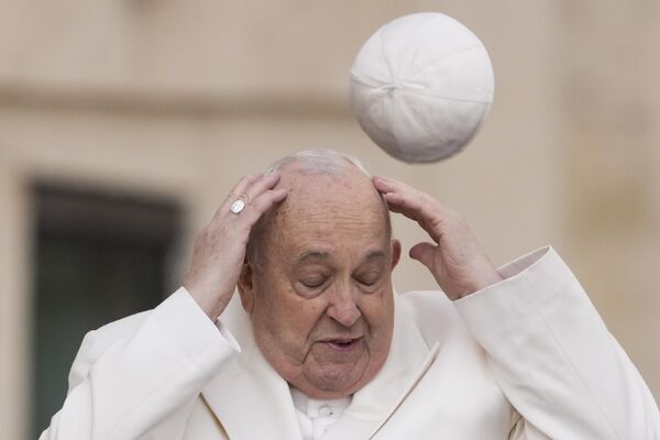 Папа Римский Франциск пытается поймать свою кепку, которую сдуло ветром в Ватикане. - Sputnik Казахстан