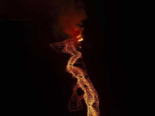 Потоки раскаленной лавы устремляются в сторону Гриндавика, землю распирает магма.На фото: вид на лаву, вытекающую из вулкана недалеко от города Гриндавик, Исландия. - Sputnik Казахстан