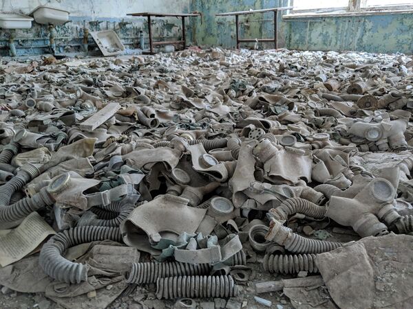 Сейчас, спустя 38 лет, Чернобыльская зона представляет собой огромную загрязненную территорию вокруг АЭС.На фото: противогазы, разбросанные в заброшенной школе в Припяти, Украина. - Sputnik Казахстан