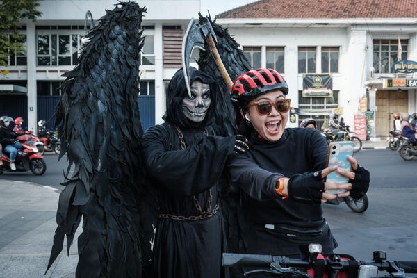 Уличный артист в костюме мистического персонажа позирует с велосипедистом в Индонезии. - Sputnik Казахстан