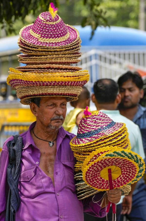 Продавец продает шляпы и ручной веер в Калькутте, Индия. - Sputnik Казахстан