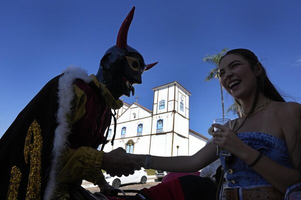 Участник, одетый в рогатую маску демона, флиртует во время празднования фестиваля “Кавальхадас”, Бразилия. - Sputnik Казахстан