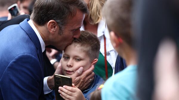 Президент Франции Эммануэль Макрон целует ребенка после голосования в первом туре парламентских выборов на избирательном участке в Ле-Туке, северная Франция - Sputnik Казахстан