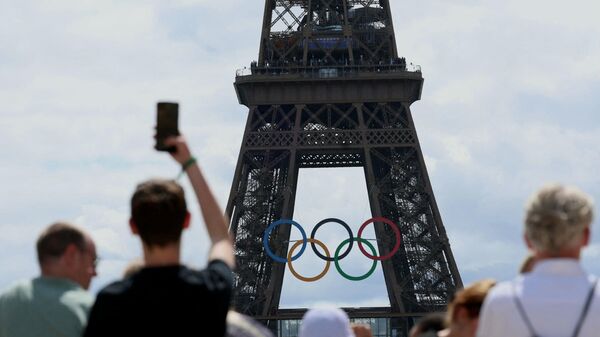 Посетители смотрят на Эйфелеву башню, украшенную Олимпийскими кольцами, в преддверии Олимпийских игр 2024 года в Париже 16 июля 2024 года - Sputnik Казахстан